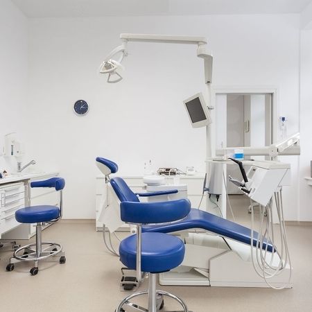 Heller und moderner zahnärztlicher Behandlungsraum mit Behandlungsstuhl, Monitor und Arbeitsbereich