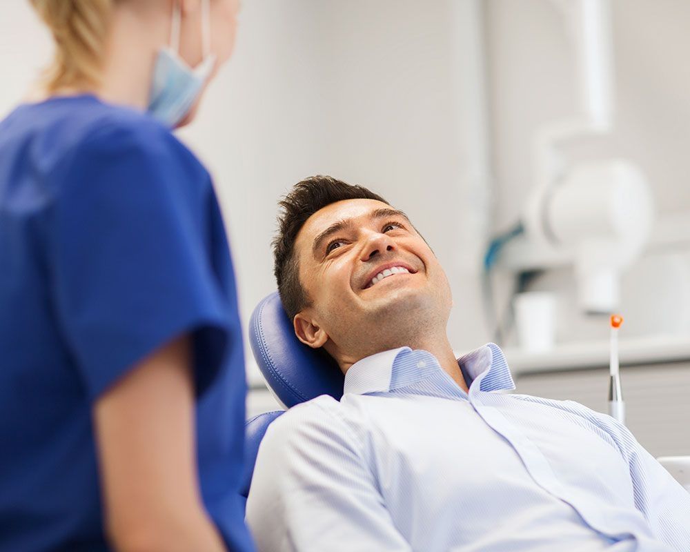 Patient im Zahnarztstuhl blickt freundlich zur behandelnden Person